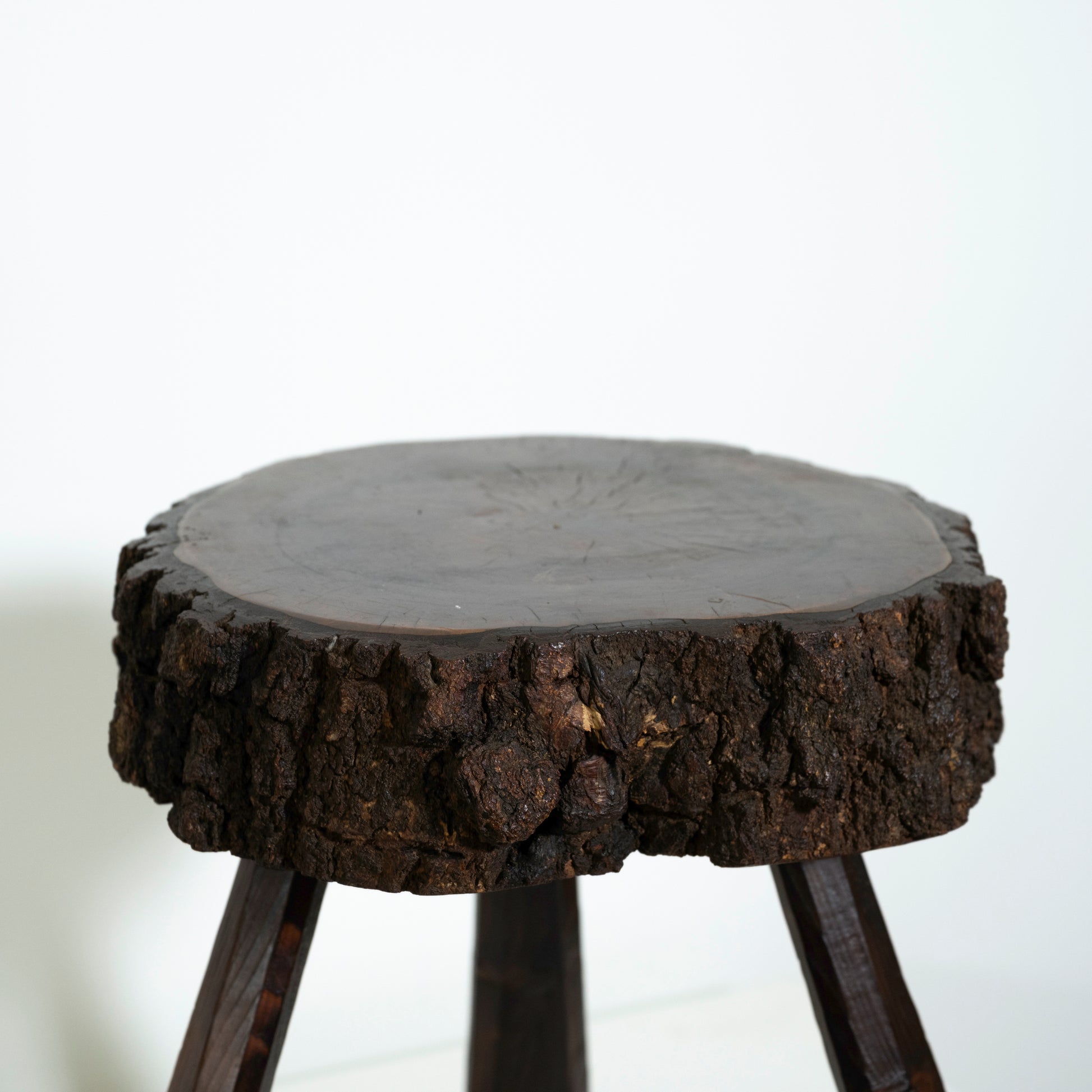 Wooden stool with a natural tree stump top on a white background