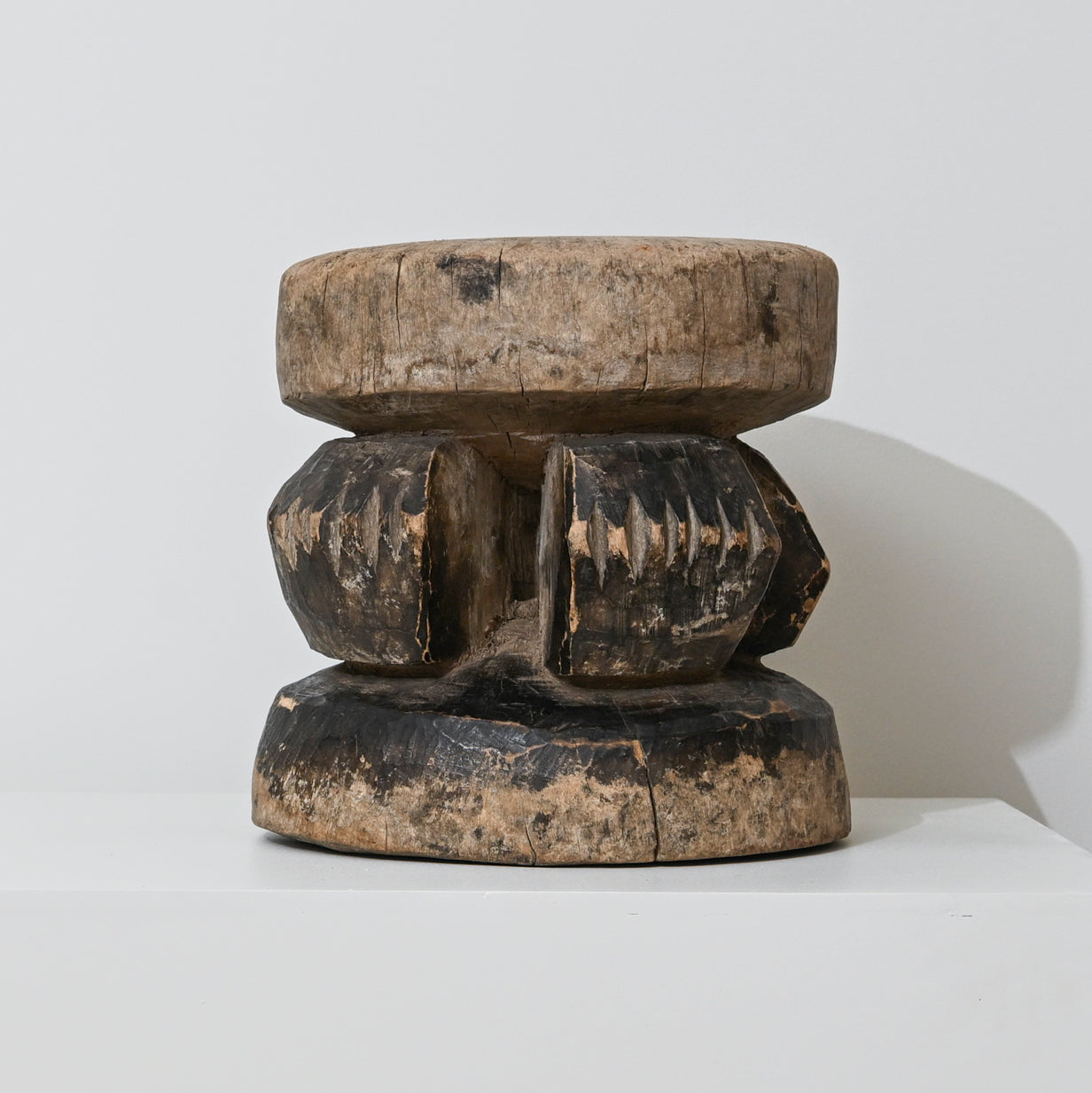 Hand carved indigenous West African stool dark brown wood with intricate carved patterns and rounded top