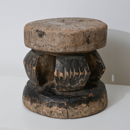 Hand carved indigenous West African wooden stool with weathered round top and dark carved geometric base