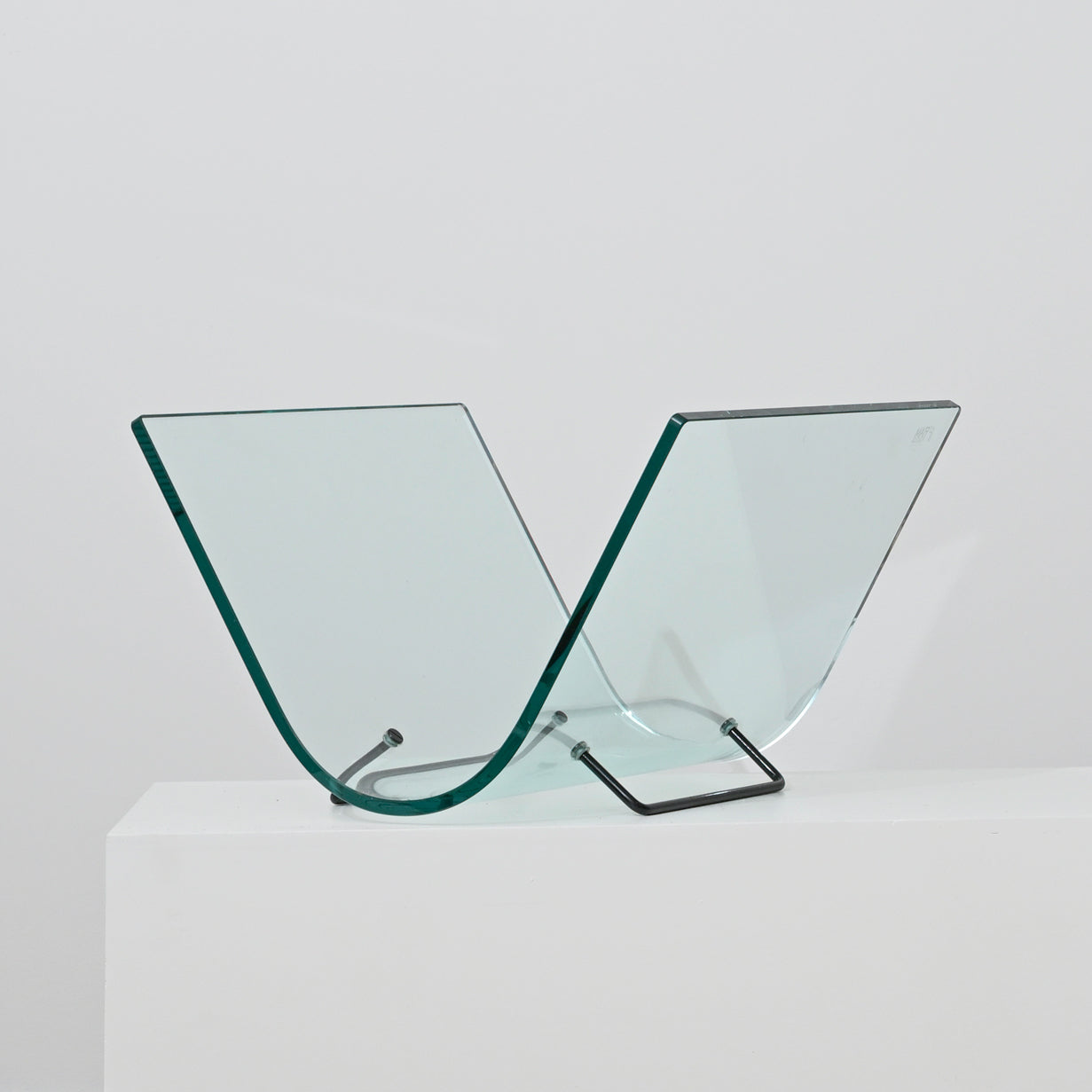 The Vintage Italian Curved Glass Magazine Holder features two V-shaped curved glass panels with a sleek metal stand, displayed on a white surface against a plain background.