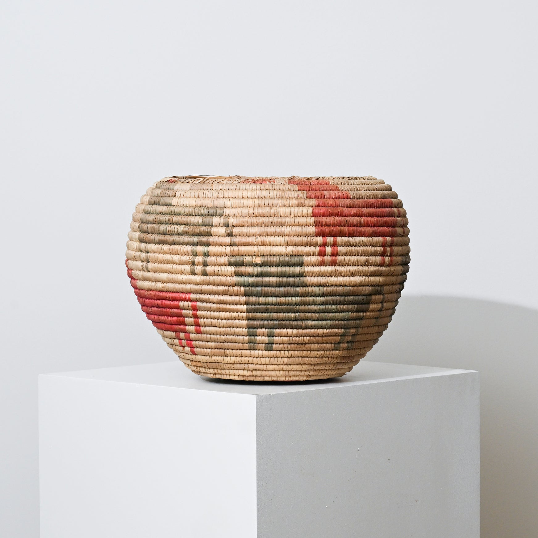 Mid 20th century Native American handwoven basket with rounded shape beige straw and red olive green geometric patterns