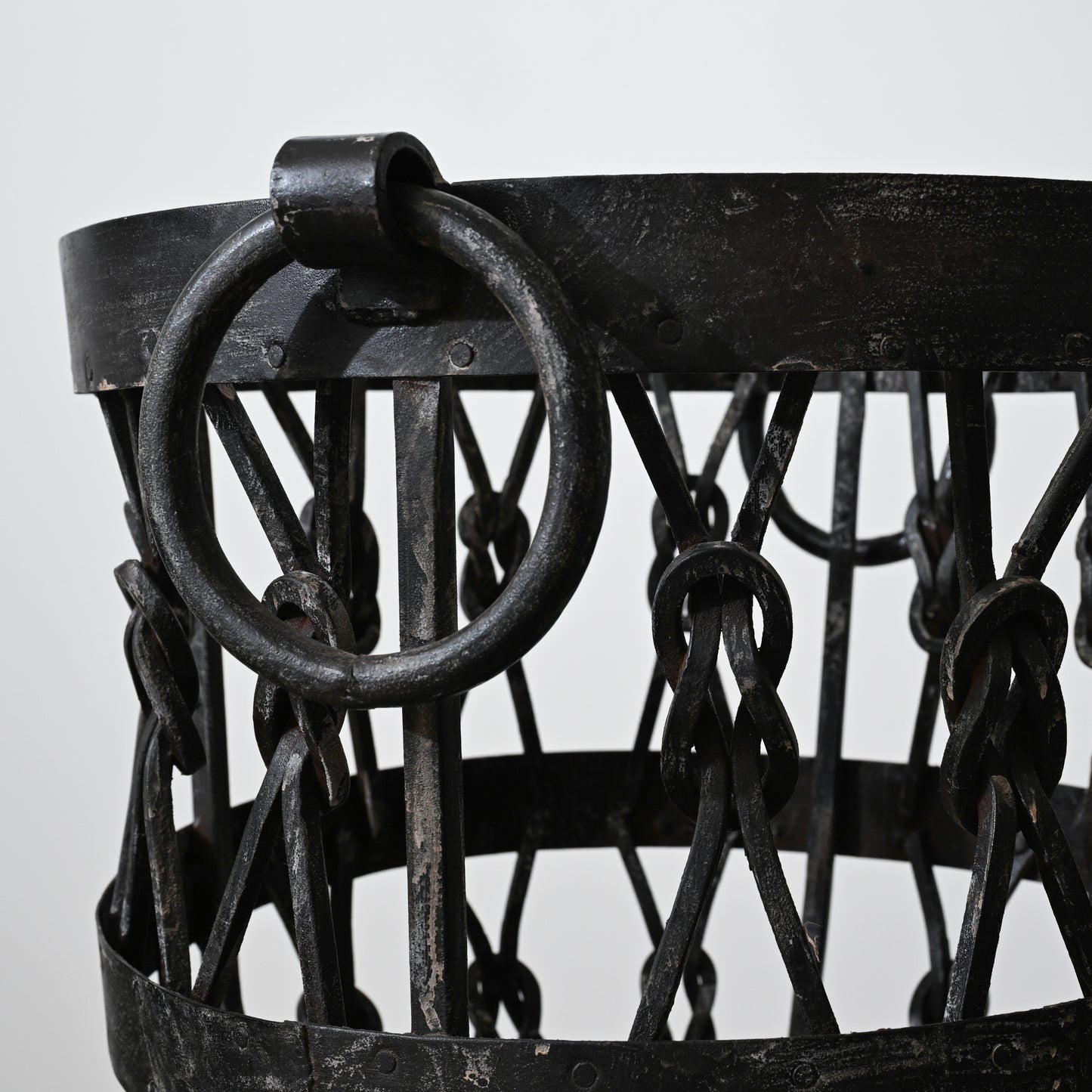 Black wrought iron wood holder basket with heavy ring handle and interwoven chain links for firewood storage