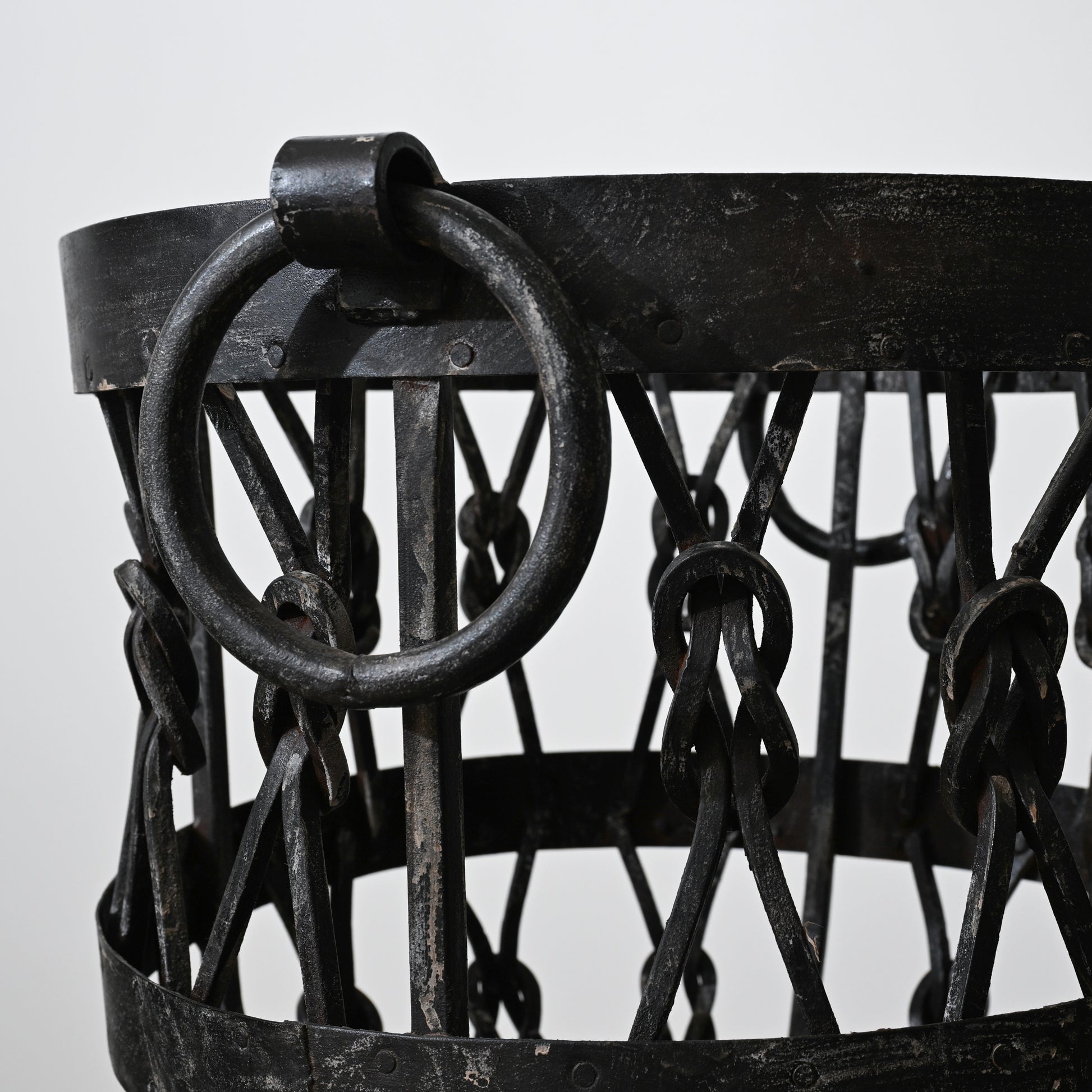 Black wrought iron wood holder basket with heavy ring handle and interwoven chain links for firewood storage