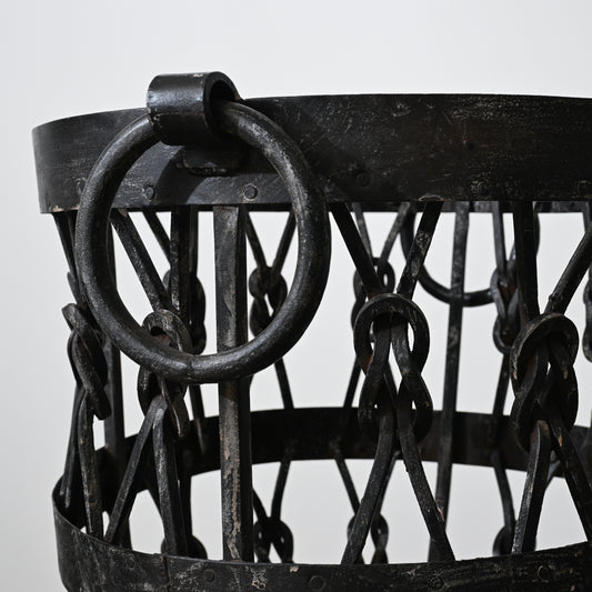 Black wrought iron wood holder basket with heavy ring handle and interwoven chain links for firewood storage