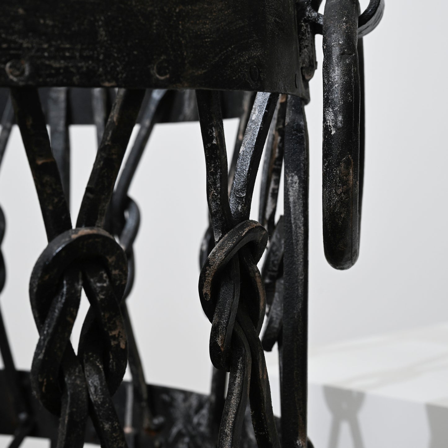 Black wrought iron lantern with intricate twisted chain links and rustic weathered finish in iron wood holder basket