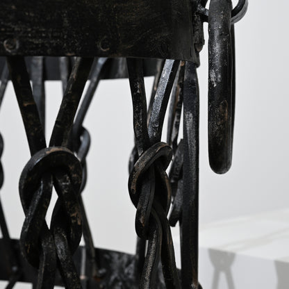 Black wrought iron lantern with intricate twisted chain links and rustic weathered finish in iron wood holder basket