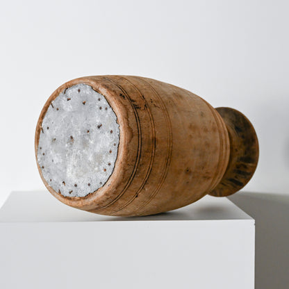 A rustic hand-carved wooden vase with a weathered brown finish and subtle horizontal grooves from primitive wood vessels