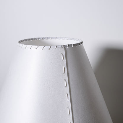 Brass and parchment table lamp with white conical lampshade featuring stitched edges and subtle texture