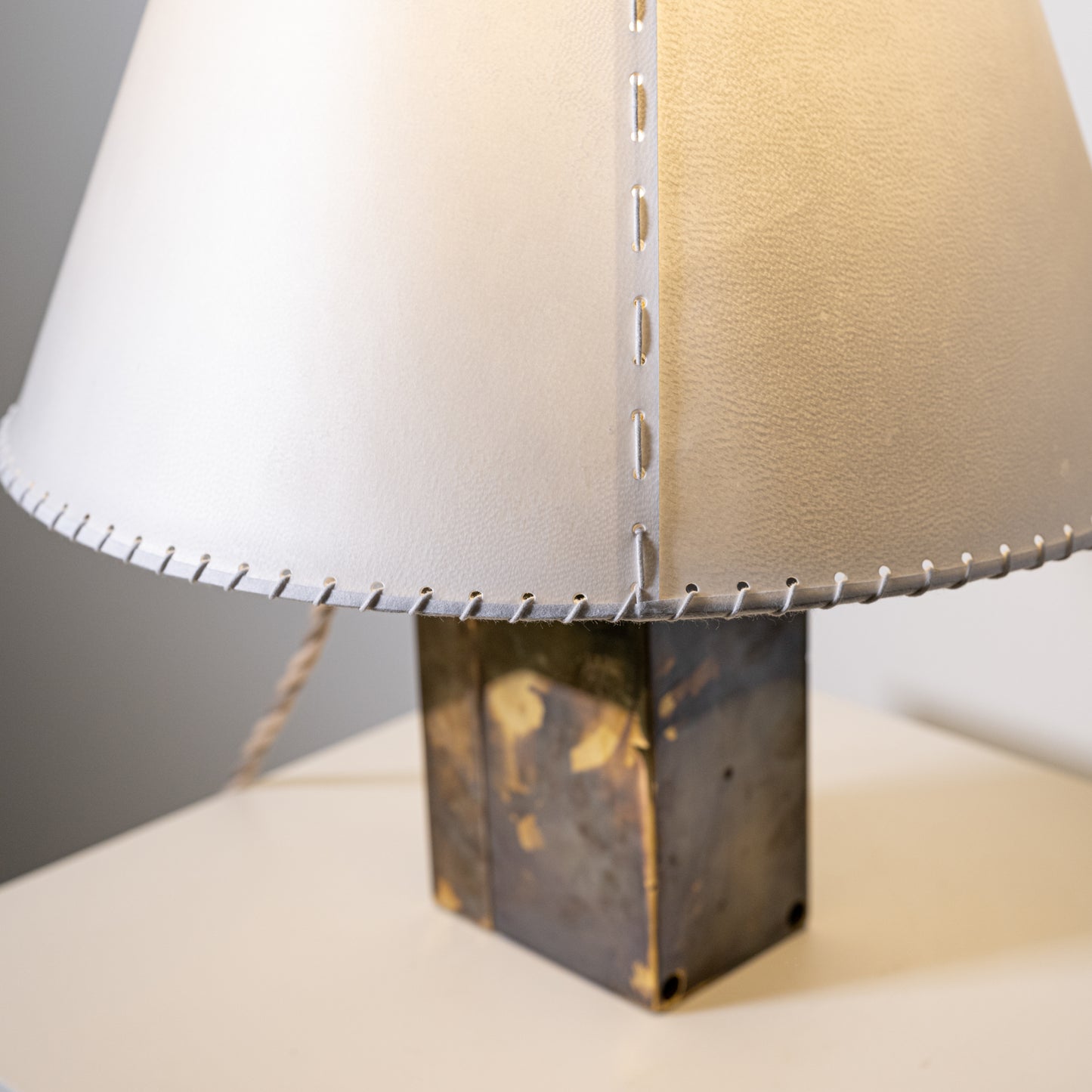Brass and parchment table lamp with a sleek two-toned white and beige leather lampshade accented by silver stitching