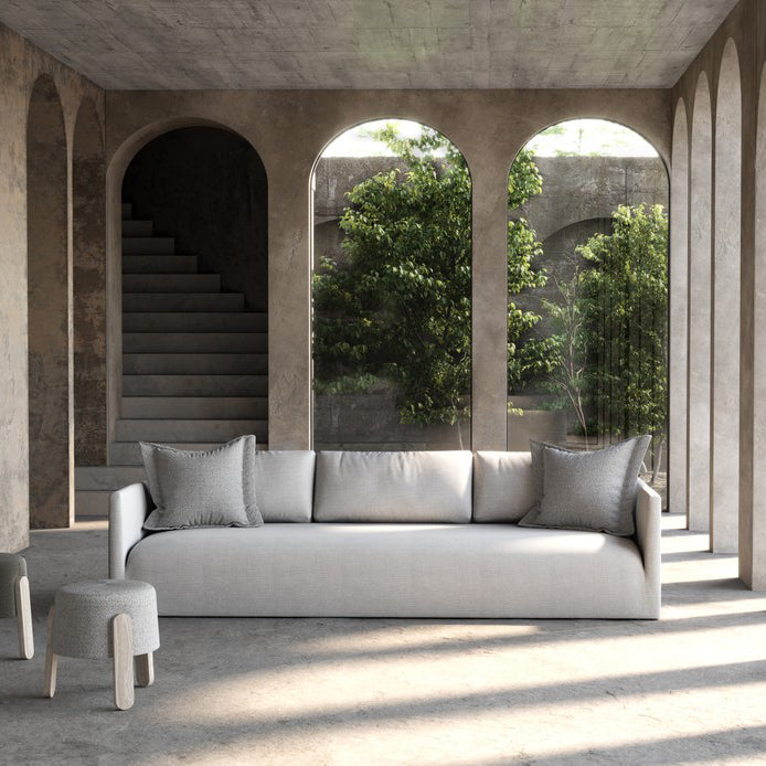 Light gray upholstered custom order Thibaut sofa with matching square pillows and minimalist design in front view