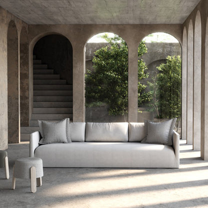 Light gray upholstered custom order Thibaut sofa with matching square pillows and minimalist design in front view