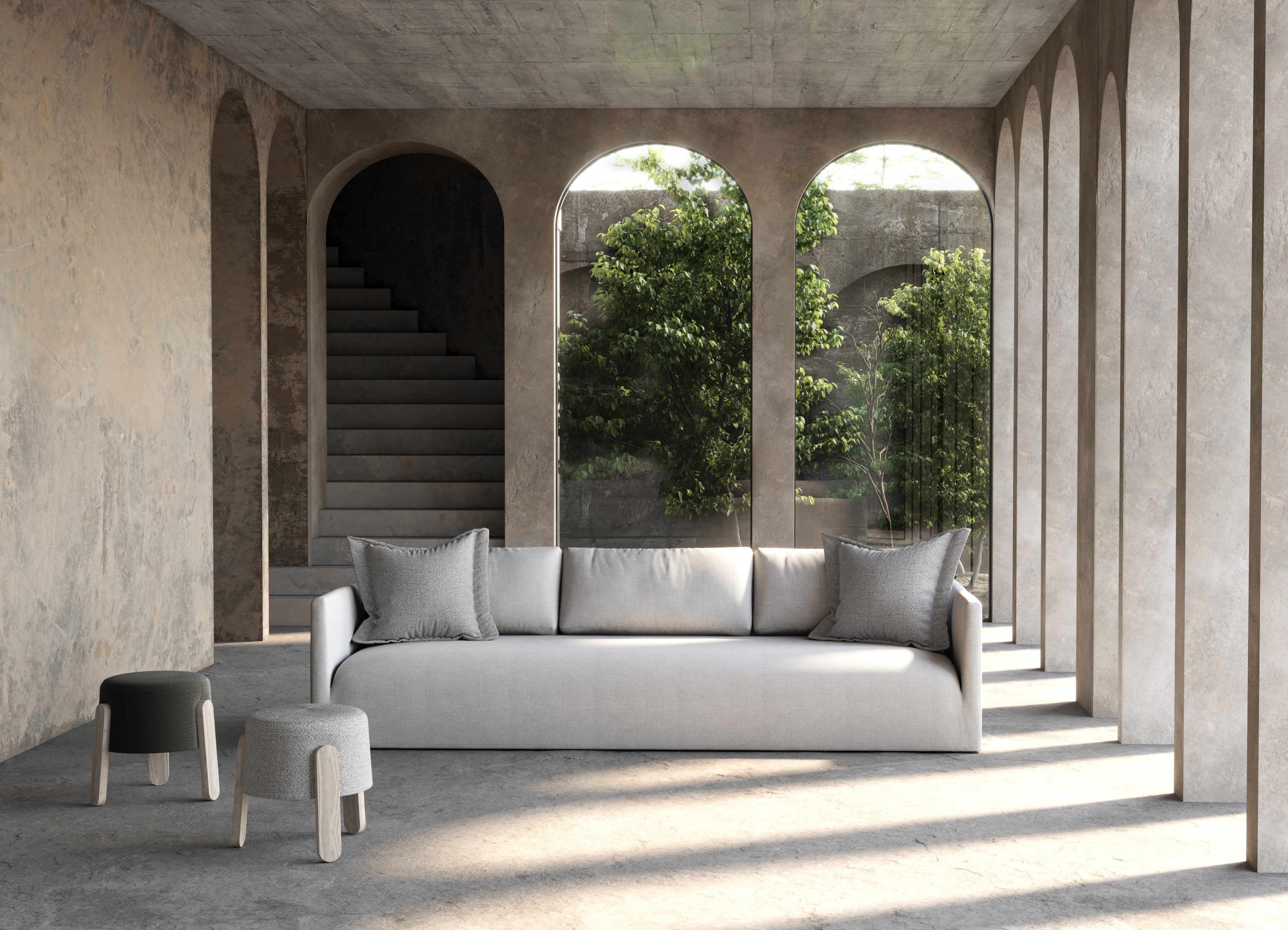 A sleek, minimalist gray sofa with clean lines and matching throw pillows sits centrally in a modern concrete-walled space.