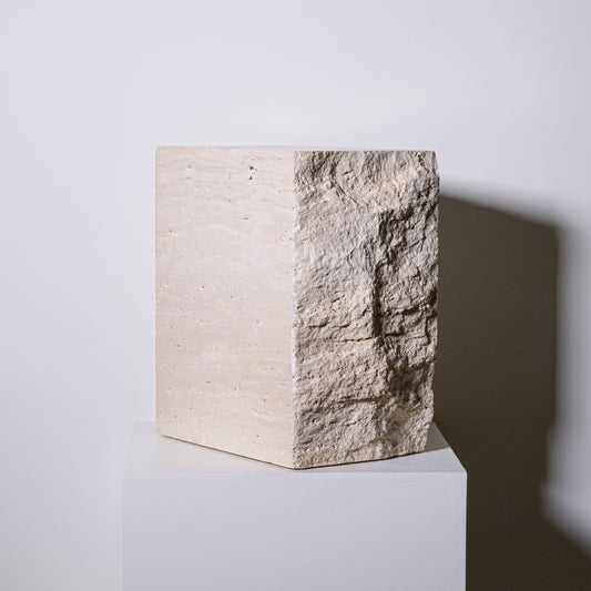 Travertine block side table in beige stone with rough textured surface on one side and smooth finish on the other