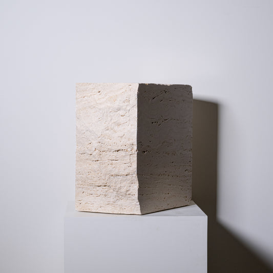 Minimalist travertine block side table with textured off-white concrete surface and smooth dark gray face