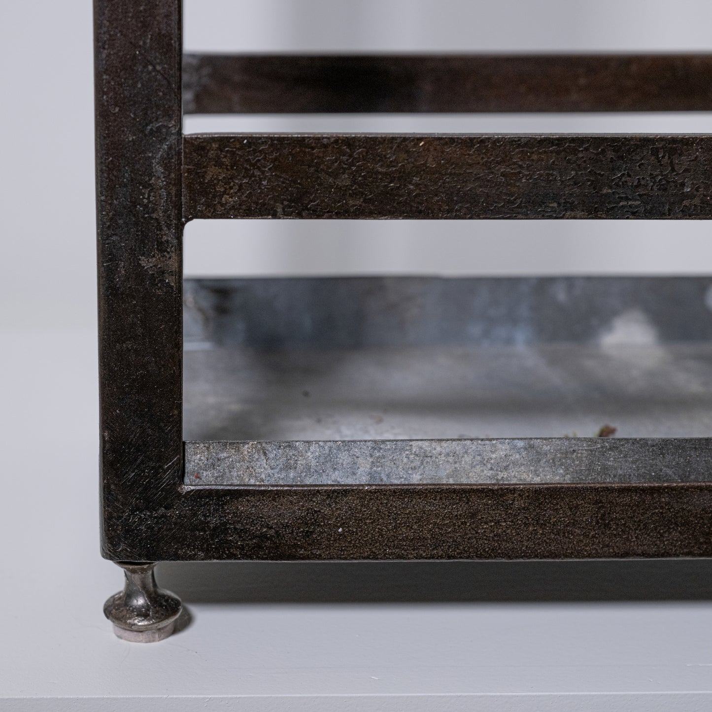 Antique umbrella stand made of rustic dark metal with distressed finish and glass panels for stylish storage