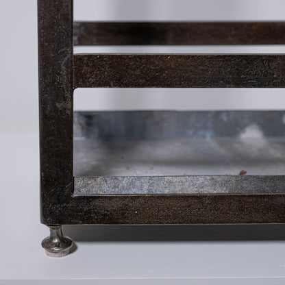 Antique umbrella stand made of rustic dark metal with distressed finish and glass panels for stylish storage