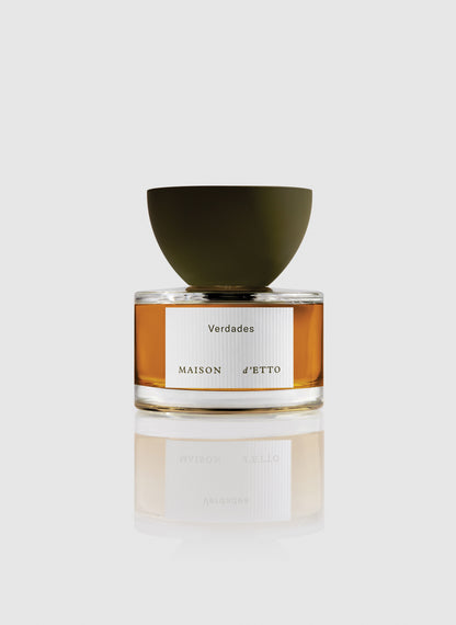 A sleek glass perfume bottle of Maison dEtto fragrance verdades with amber liquid and a matte olive green bowl shaped cap
