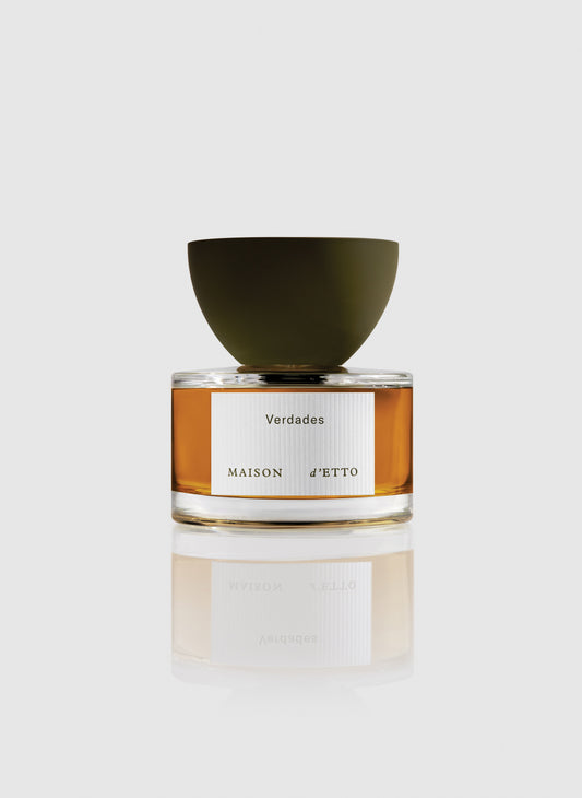 A sleek glass perfume bottle of Maison dEtto fragrance verdades with amber liquid and a matte olive green bowl shaped cap