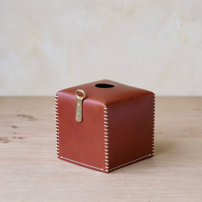 Brown leather tissue box cover with white stitching and brass keyhole clasp for stylish home use