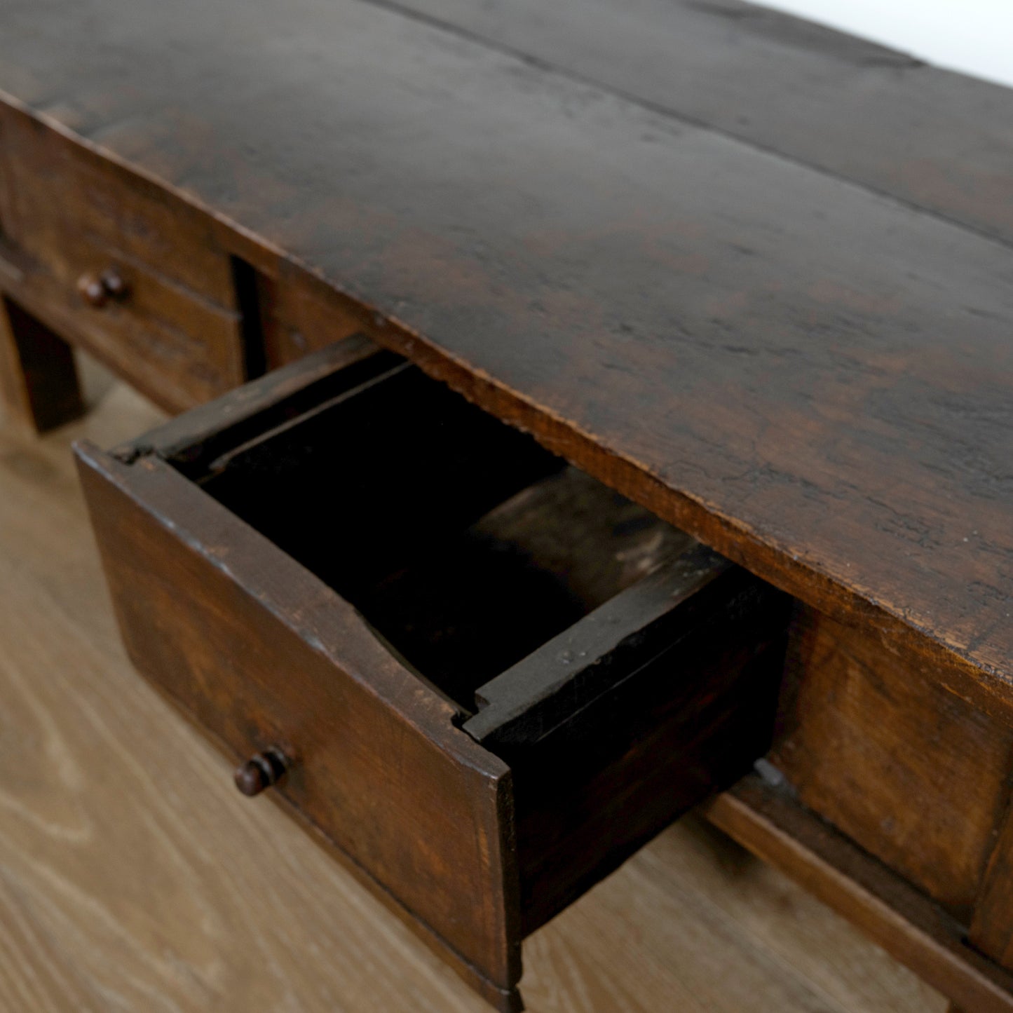 Wooden desk with an open drawer on a wooden floor