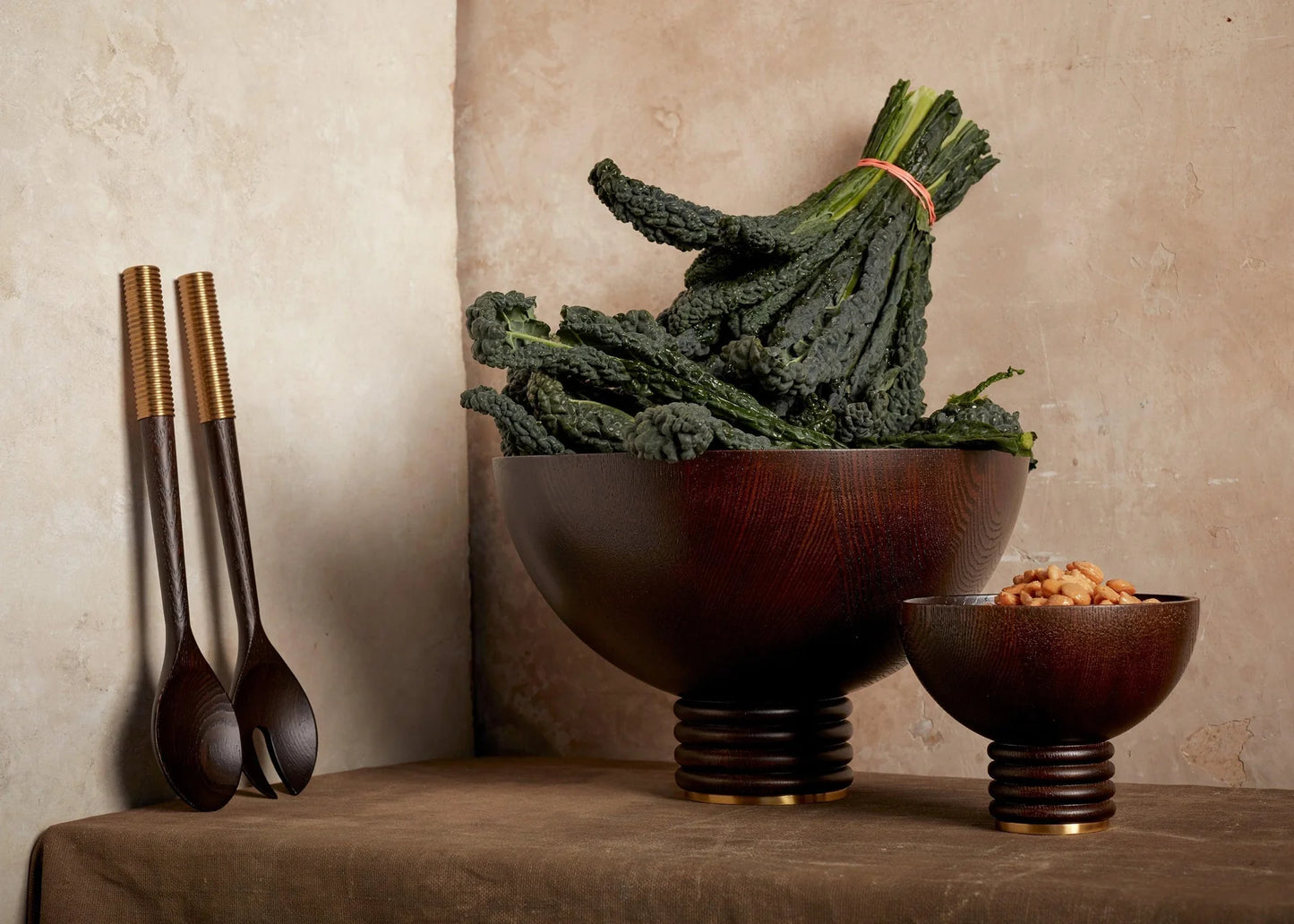 Dark wood alhambra bowl with ribbed base and gold-toned rim filled with curly kale
