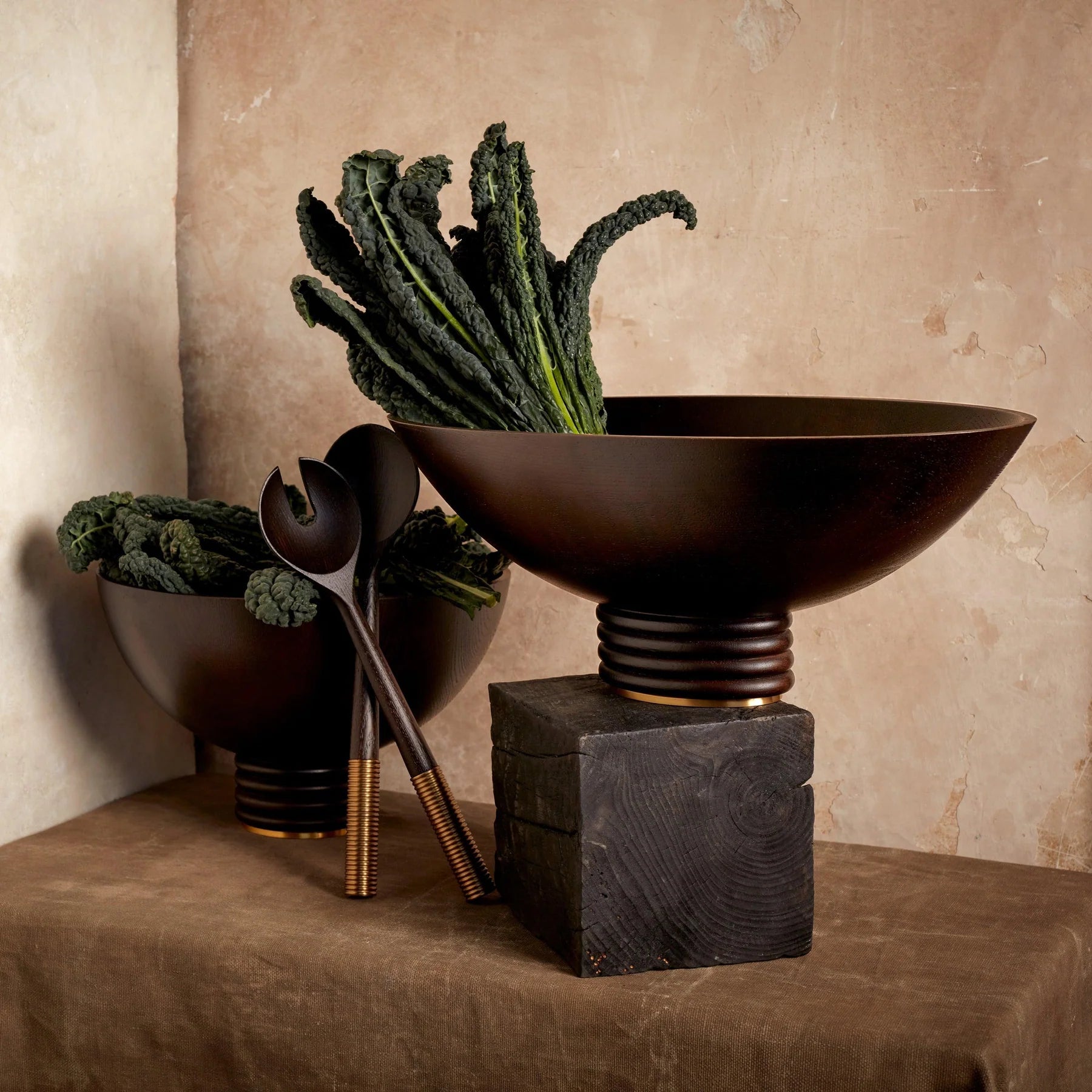 Dark brown ceramic alhambra bowl with fluted pedestal base and gold accents filled with curly kale