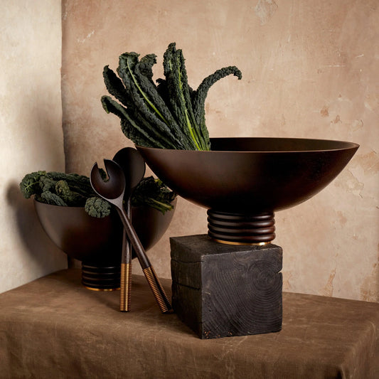 Dark brown ceramic alhambra bowl with fluted pedestal base and gold accents filled with curly kale