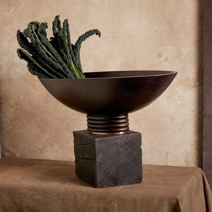 Dark bronze alhambra oval bowl with ribbed pedestal base resting on rustic wooden block