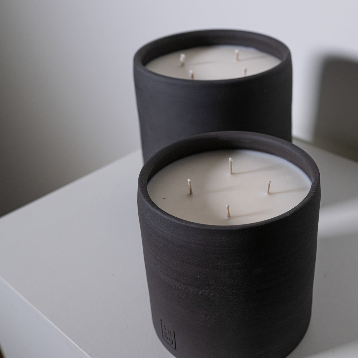 Black cylindrical candle holder candle noel with three white wicks for decorative and ambient lighting