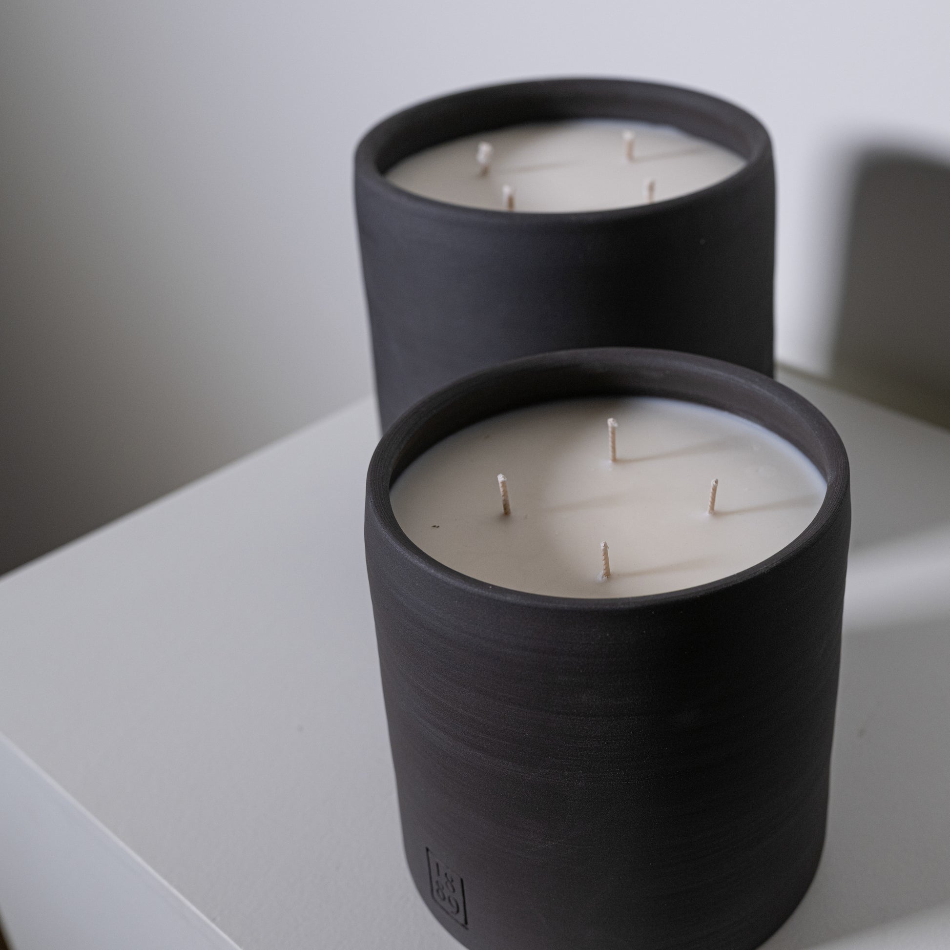 Black cylindrical candle holder with three white wicks from candle savu for ambient home lighting