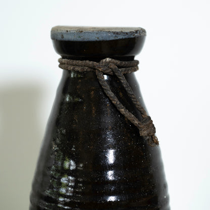 Black ceramic bottle with a rope tie on a white background