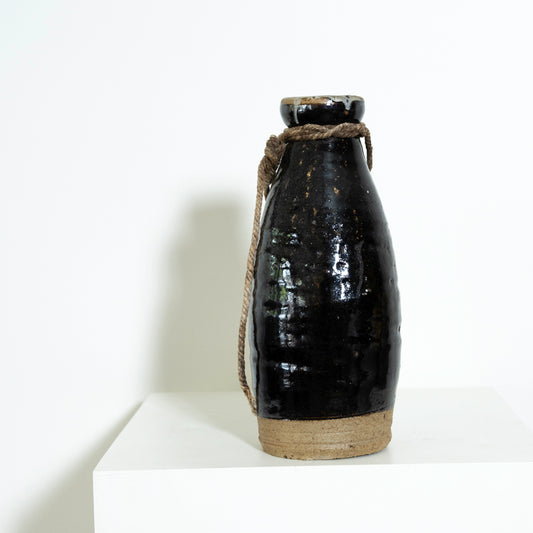 Black ceramic bottle with a rope handle on a white background