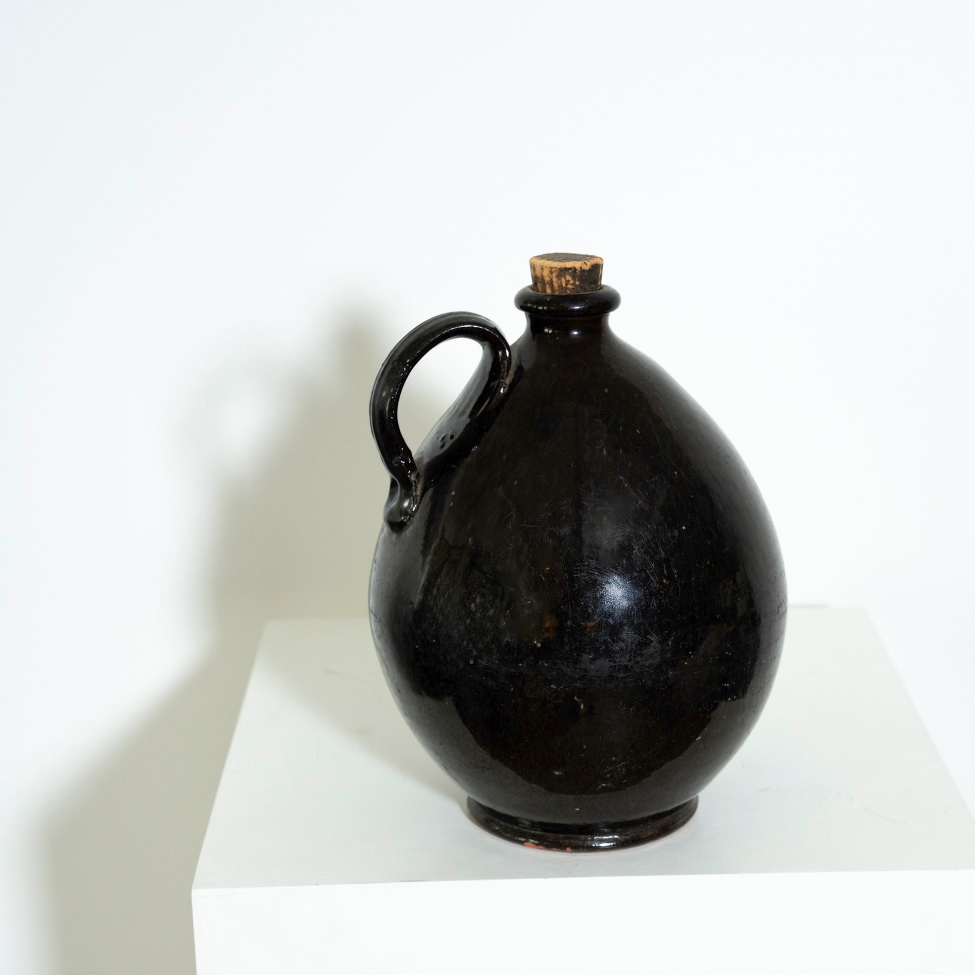 Black ceramic jug with a cork stopper on a white surface