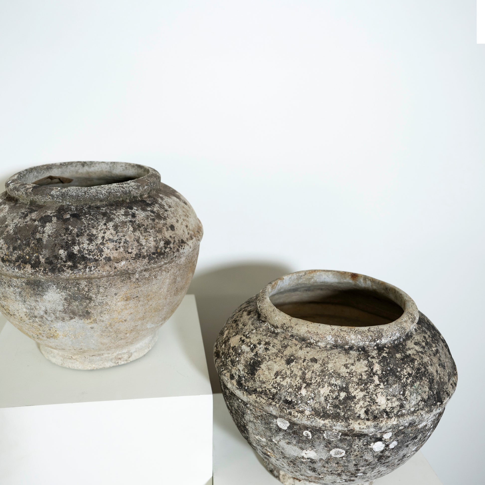 Two rustic ceramic pots on a white surface with a white background