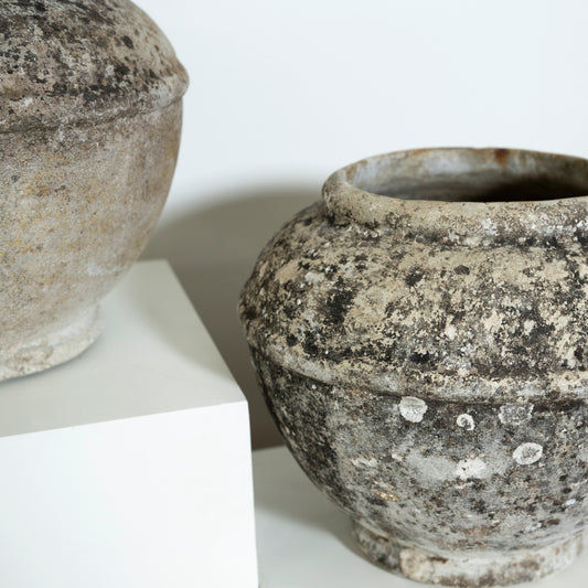 Two rustic stone pots on a white surface with a light gray background
