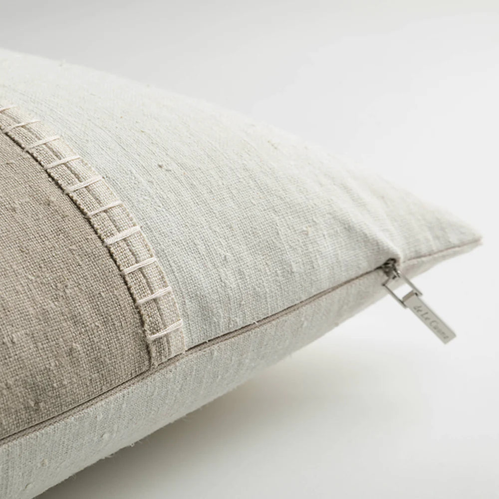 A light gray painted linen panel pillow with subtle textured weave and decorative stitched edge panel