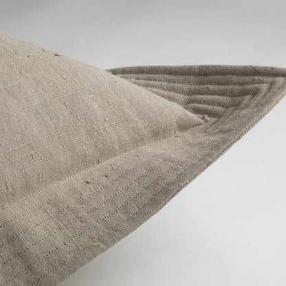 Beige linen quilted edge pillow in cement color with visible stitching and a textured woven surface