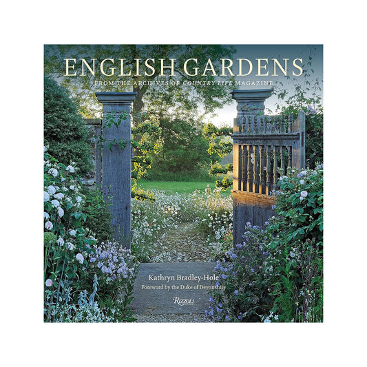 A weathered wooden garden gate with ornate carvings flanked by lush greenery and white flowers in english gardens