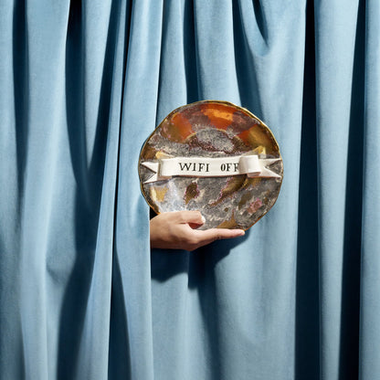 A hand-painted ceramic plate with gold rim and amber silver glaze featuring a white ribbon banner reading wifi off