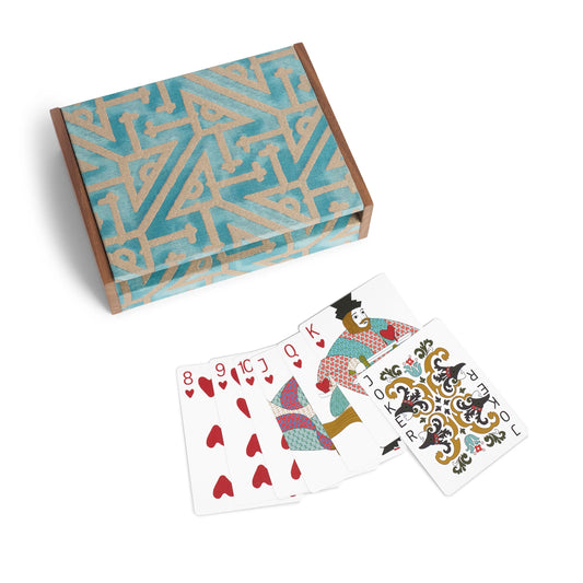 A set of Fortuny playing cards with ornate red and teal designs displayed with a matching patterned box