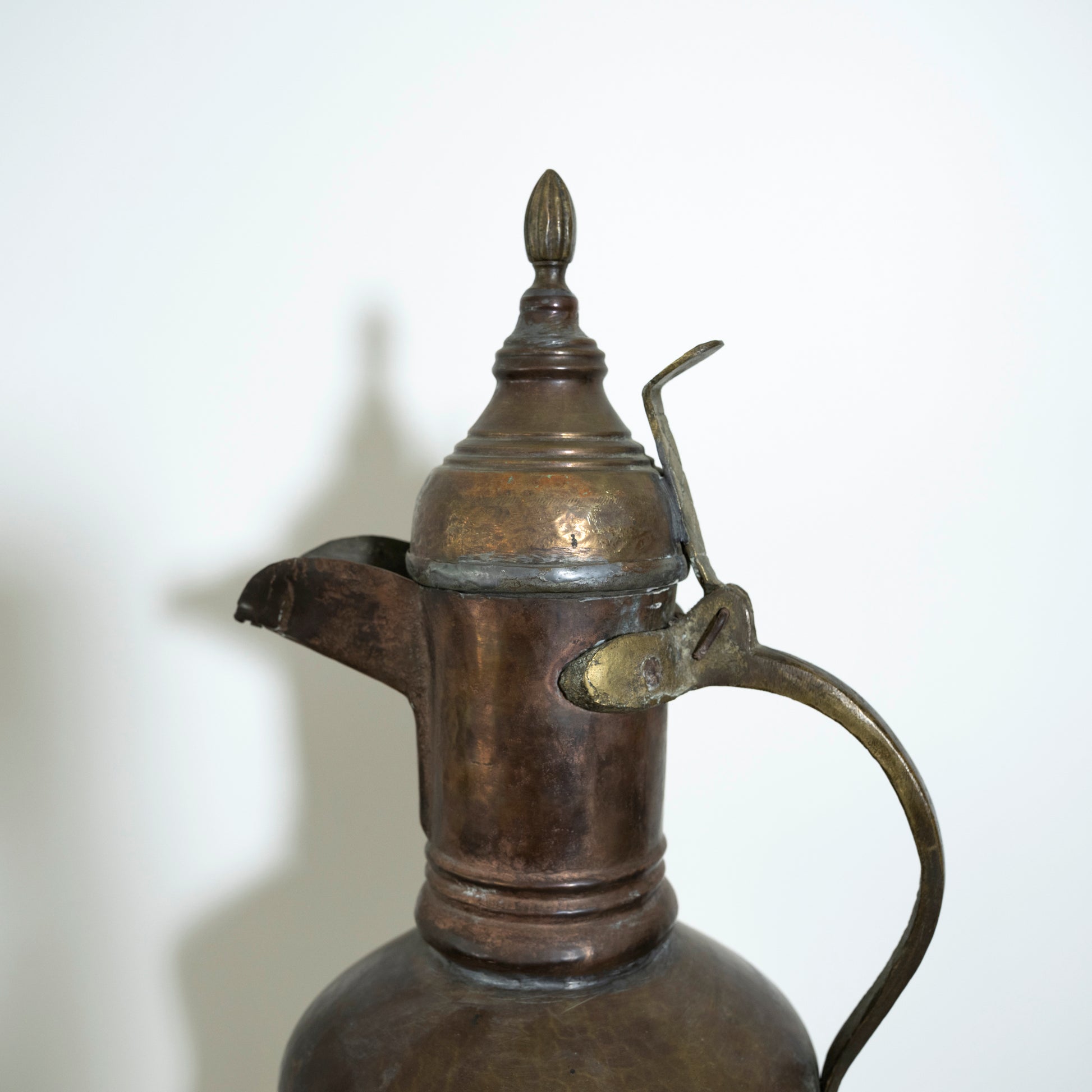 Bronze or brass pitcher with a lid on a white background