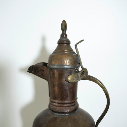 Bronze or brass pitcher with a lid on a white background