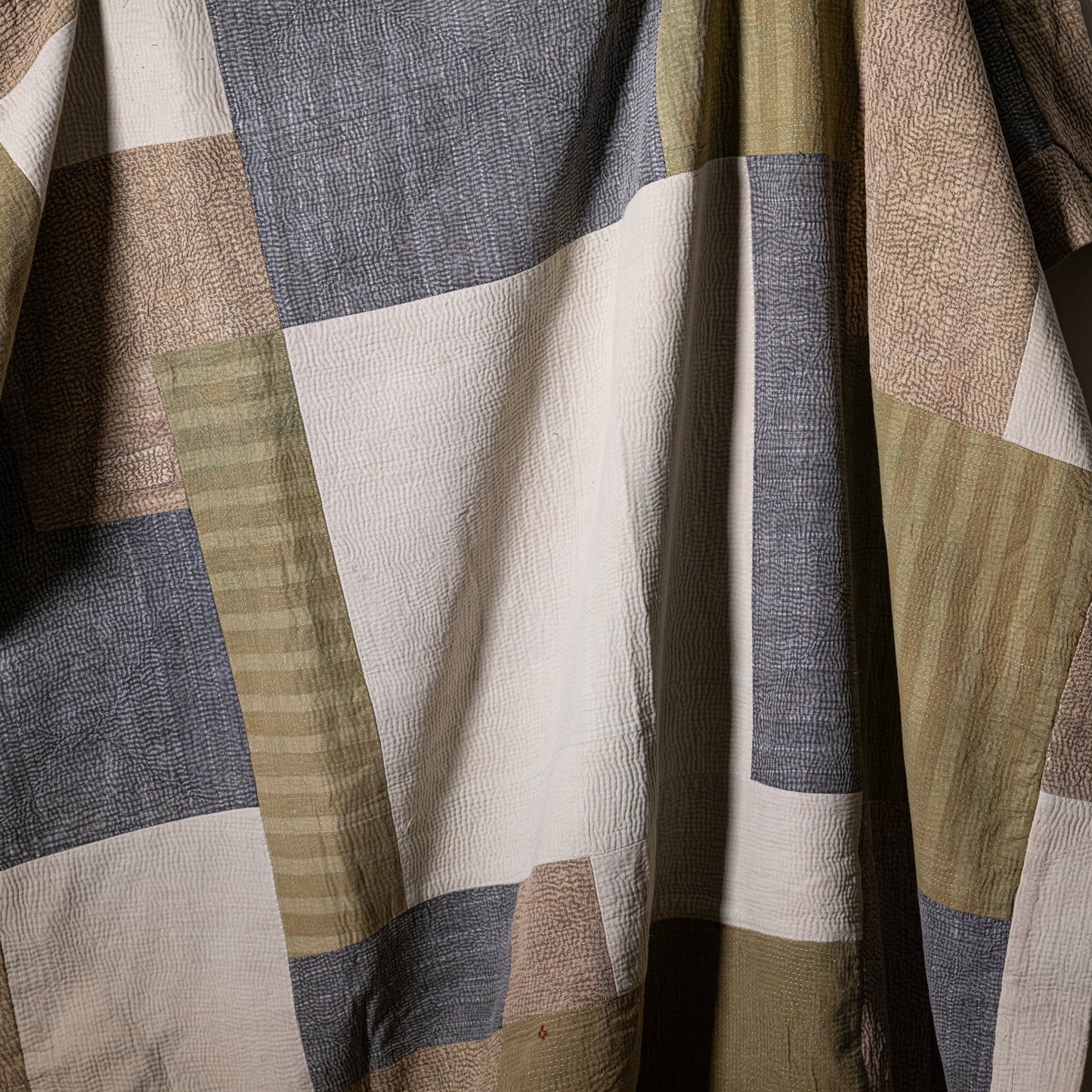 Mosaic quilt patchwork design with textured earth-toned fabric squares in beige olive green and gray