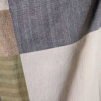 Mosaic quilt featuring textured hand-quilted patchwork panels in muted gray beige and olive green tones