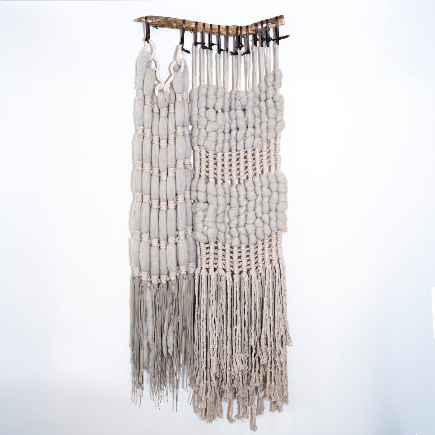Macrame wall hanging with white and gray strings on a white background