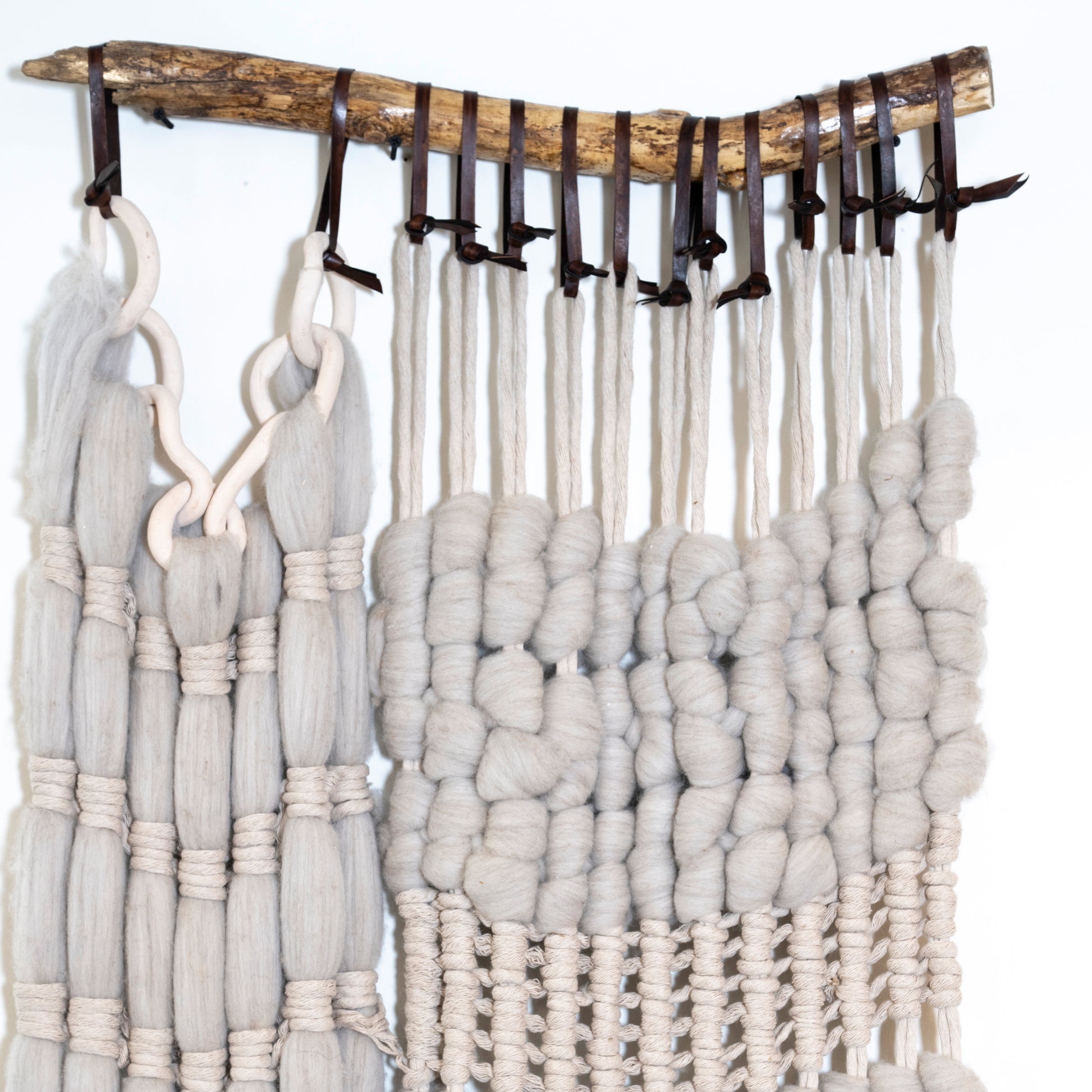 Textured fabric hanging from a wooden rod with hooks on a white background