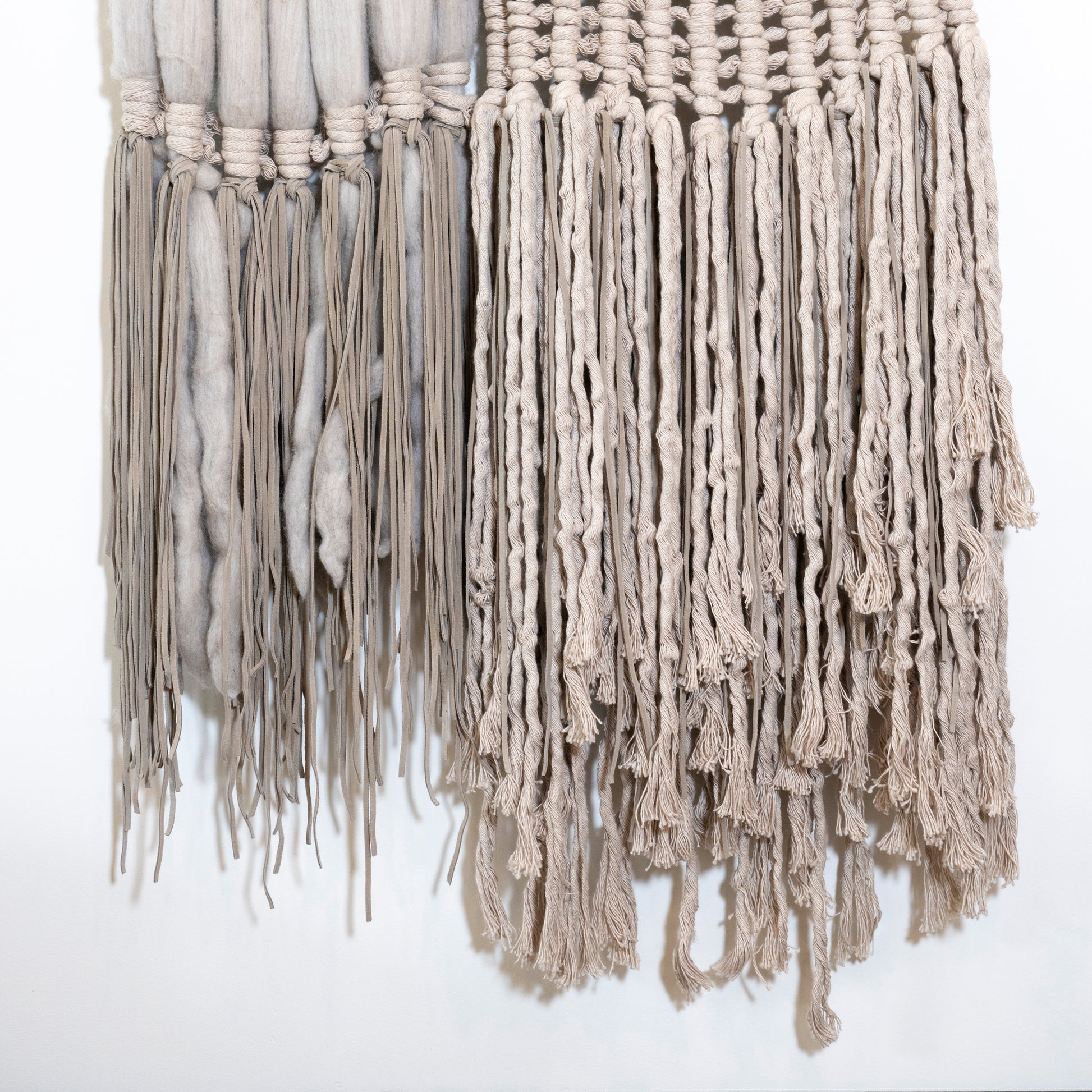 Macrame wall hanging with beige threads on a white background