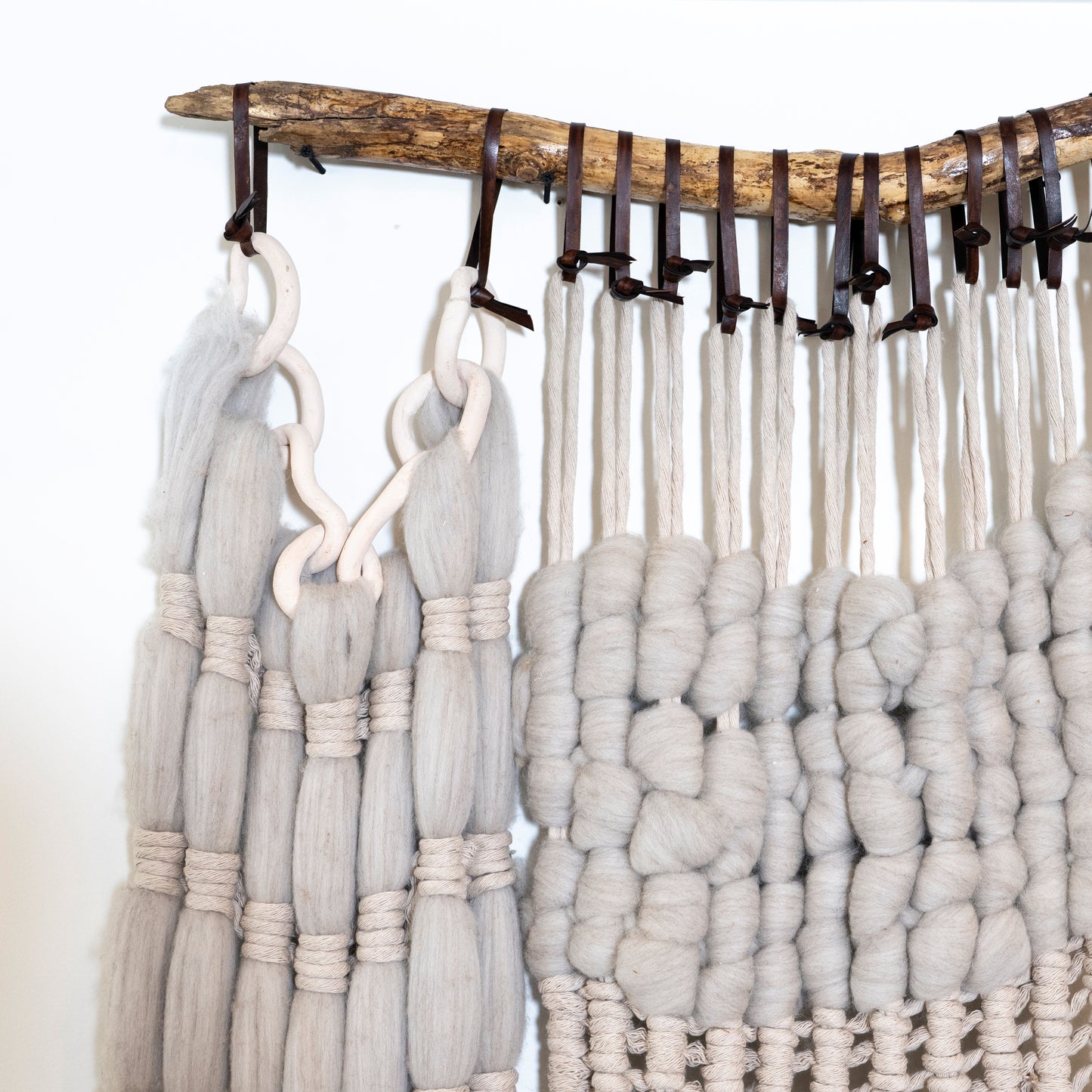 Textile art piece with braided yarn on a wooden frame against a white background