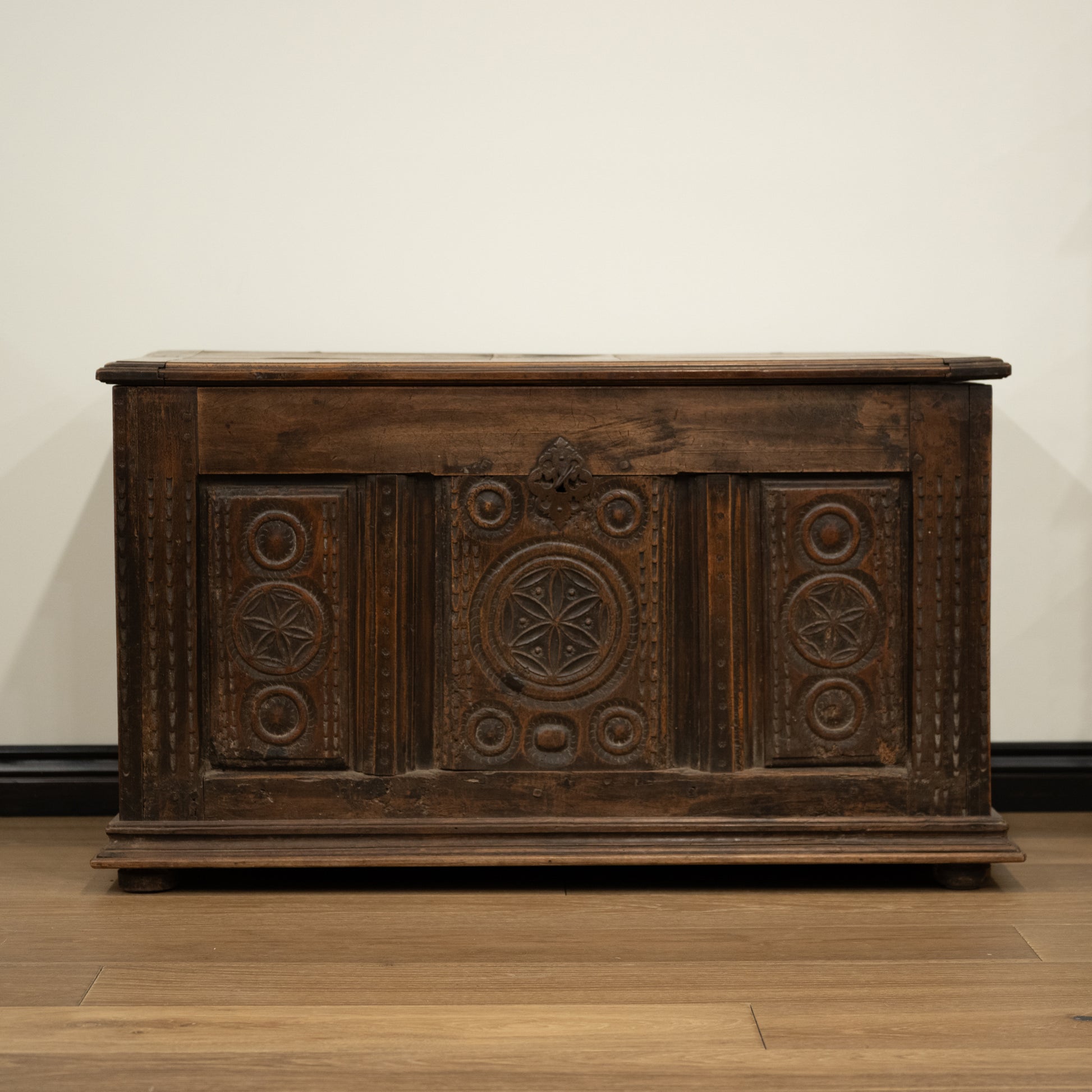 Dark brown 19th century french wooden mountain chest with intricate carved patterns and rustic worn finish