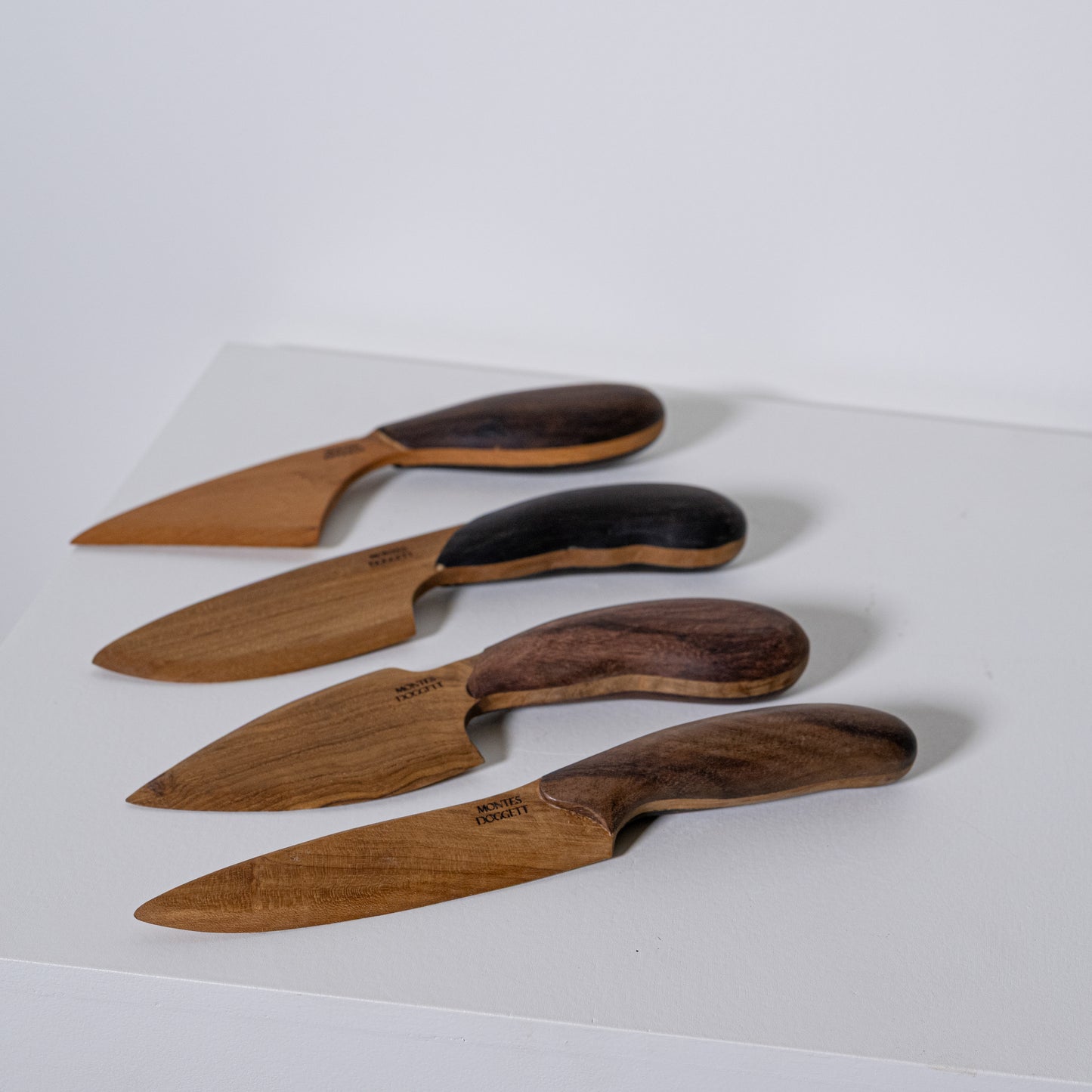 Set of four teak and sono wooden cheese knives with handcrafted natural and dark wood handles for serving cheese